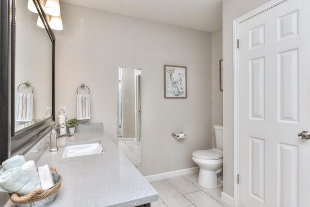 bathroom with toilet, tile patterned flooring, vanity, and baseboards