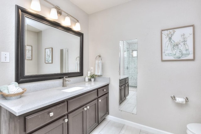 full bath featuring tile patterned floors, vanity, a tile shower, baseboards, and toilet