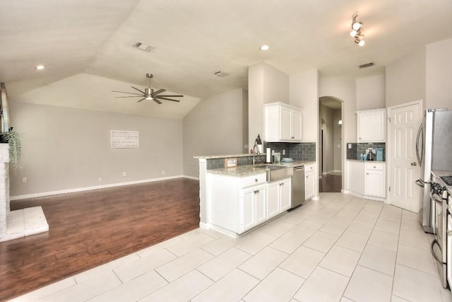kitchen with dishwasher, arched walkways, a ceiling fan, lofted ceiling, and decorative backsplash