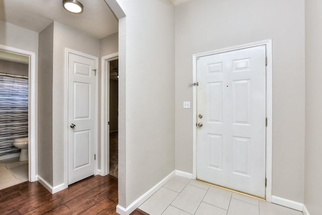 entryway featuring arched walkways, baseboards, and light wood-style flooring