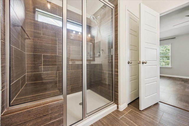 full bath with a shower stall, wood finished floors, and baseboards