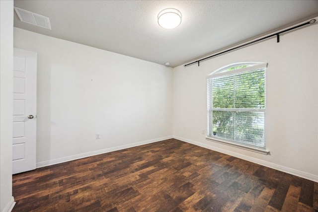 spare room featuring dark wood-type flooring and baseboards