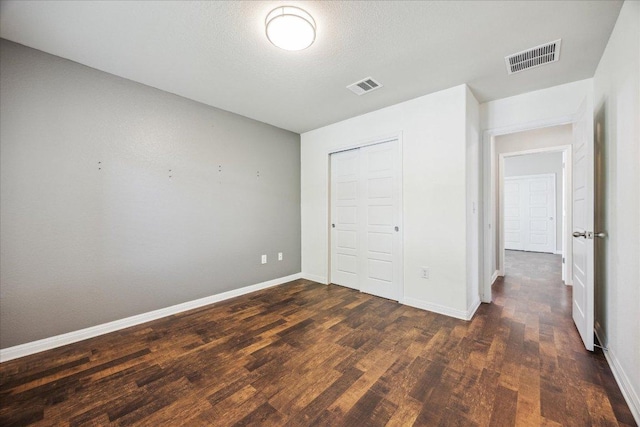 unfurnished bedroom with wood finished floors, baseboards, and a closet