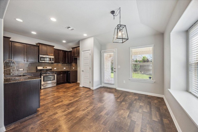 kitchen with stainless steel appliances, vaulted ceiling, a sink, tasteful backsplash, and dark brown cabinetry