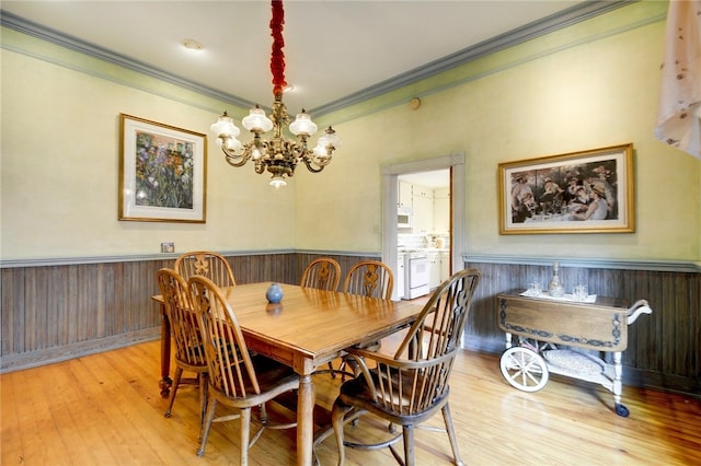 101 Short St, Smithville, TX 78957 - dining space with crown molding, a wainscoted wall, a chandelier, wood finished floors, and wooden walls