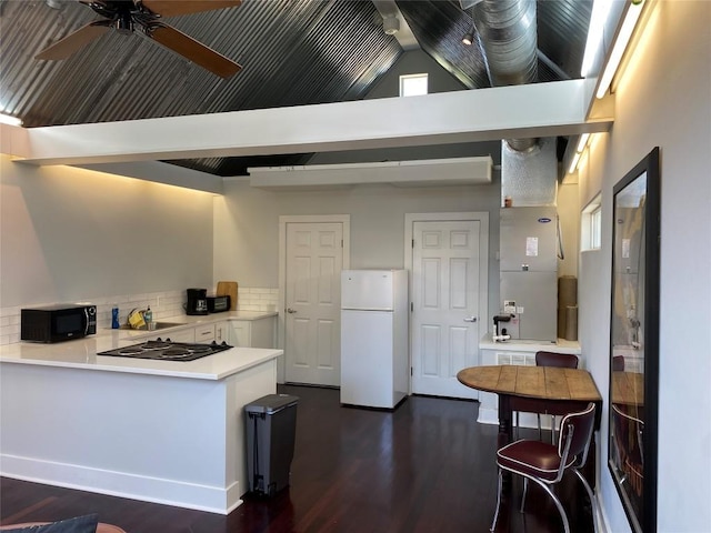 101 Short St, Smithville, TX 78957 - kitchen with black appliances, dark wood finished floors, a ceiling fan, a peninsula, and backsplash