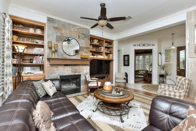 109 Cattle Trail Way, Georgetown, TX 78633 - living room with healthy amount of natural light, crown molding, a tiled fireplace, and built in shelves