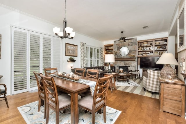 109 Cattle Trail Way, Georgetown, TX 78633 - dining area featuring crown molding, ceiling fan, a fireplace, wood finished floors, and a chandelier