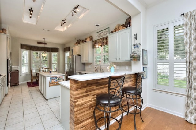 109 Cattle Trail Way, Georgetown, TX 78633 - kitchen with freestanding refrigerator, baseboards, light countertops, a center island, and a peninsula