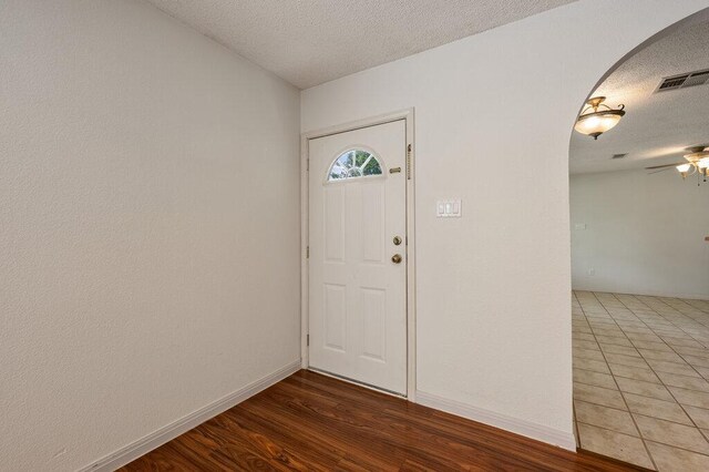 8309 Burrell Dr, Austin, TX 78757 - foyer featuring arched walkways, a textured ceiling, baseboards, a ceiling fan, and wood finished floors