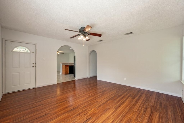8309 Burrell Dr, Austin, TX 78757 - unfurnished living room with a ceiling fan, arched walkways, wood finished floors, a textured ceiling, and baseboards