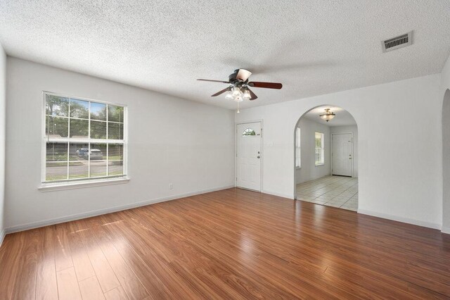 8309 Burrell Dr, Austin, TX 78757 - empty room with ceiling fan, arched walkways, wood finished floors, a textured ceiling, and baseboards