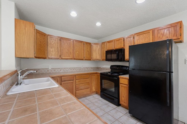 8309 Burrell Dr, Austin, TX 78757 - kitchen featuring black appliances, a sink, tile counters, a textured ceiling, and recessed lighting