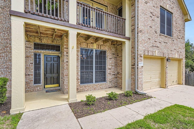 property entrance featuring a balcony, an attached garage, brick siding, concrete driveway, and a porch