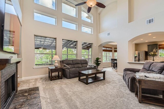 living room with a high ceiling, baseboards, a ceiling fan, arched walkways, and carpet floors