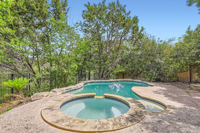 view of pool with a fenced backyard and a pool with connected hot tub