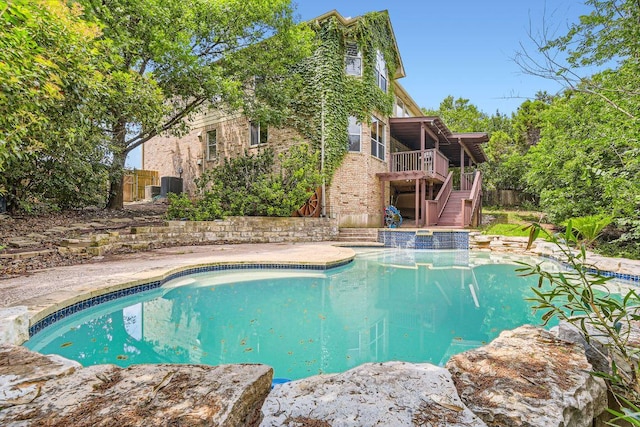 outdoor pool featuring stairway, cooling unit, a wooden deck, and fence