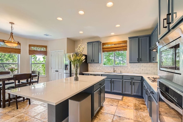 kitchen featuring appliances with stainless steel finishes, a sink, light countertops, decorative backsplash, and recessed lighting