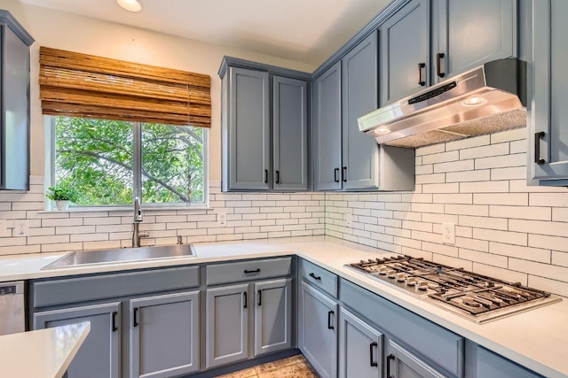 kitchen with under cabinet range hood, a sink, stainless steel gas stovetop, and light countertops