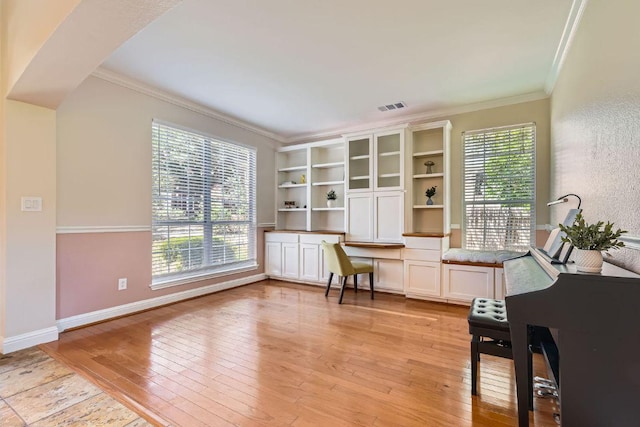 office space featuring crown molding, light wood-type flooring, and baseboards