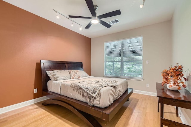 bedroom featuring track lighting, light wood-type flooring, baseboards, and ceiling fan