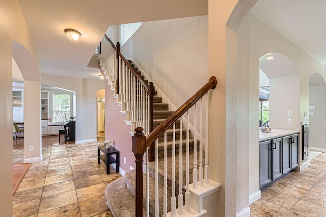 stairway featuring baseboards and stone tile floors
