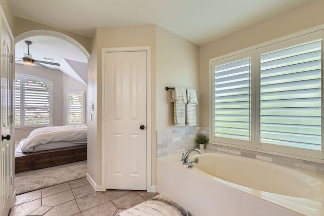 ensuite bathroom with a bath, tile patterned flooring, a ceiling fan, and baseboards