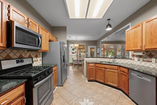kitchen with appliances with stainless steel finishes, a sink, decorative backsplash, and light tile patterned flooring