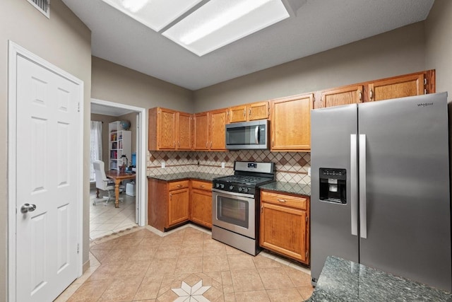kitchen featuring stainless steel appliances, backsplash, light tile patterned floors, and brown cabinets