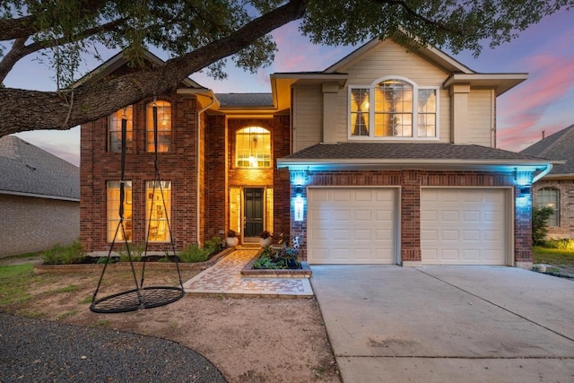 traditional home featuring an attached garage, driveway, and brick siding