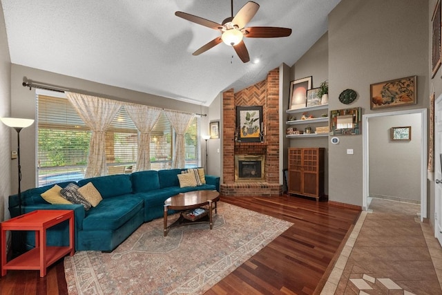 living room with vaulted ceiling, a ceiling fan, a brick fireplace, baseboards, and wood finished floors