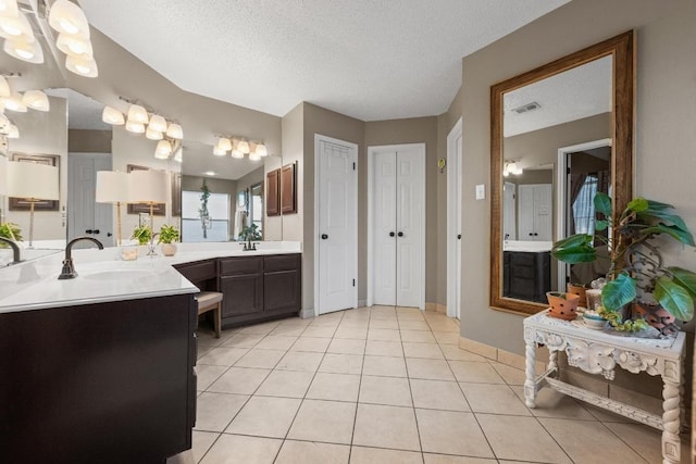 full bath with tile patterned floors, vanity, a textured ceiling, and baseboards