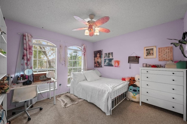 carpeted bedroom with a textured ceiling, a desk, and ceiling fan