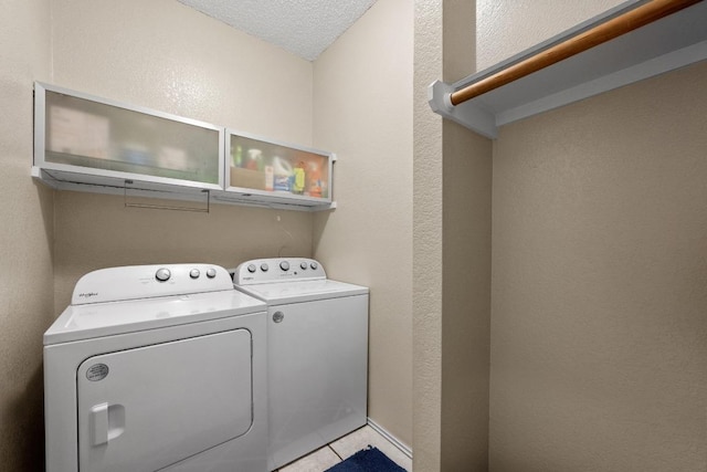 laundry room with washer and dryer, light tile patterned floors, a textured wall, and a textured ceiling