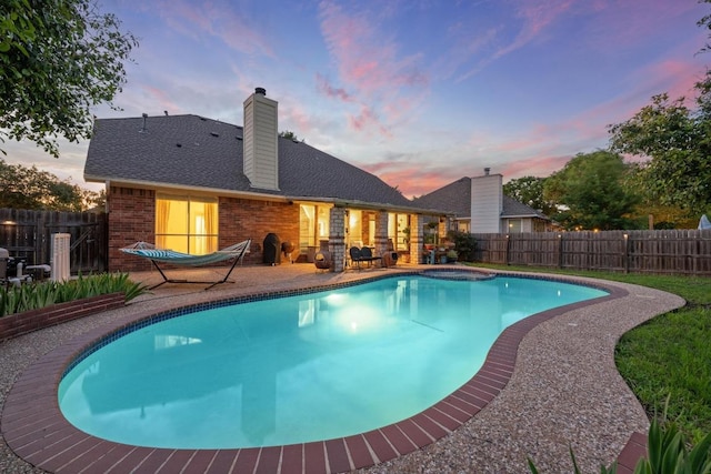 pool at dusk featuring a patio area and a fenced backyard