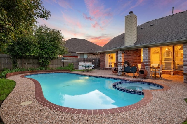 pool at dusk featuring a fenced backyard, a patio, and a pool with connected hot tub