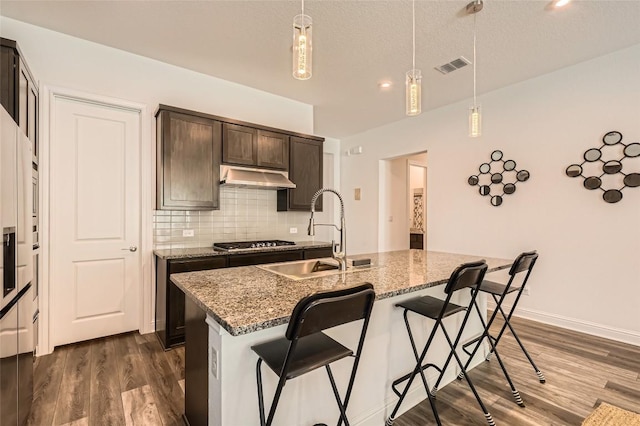 4608 Modena Bay Bnd, Leander, TX 78641 - kitchen featuring under cabinet range hood, dark wood-style floors, tasteful backsplash, a kitchen breakfast bar, and recessed lighting