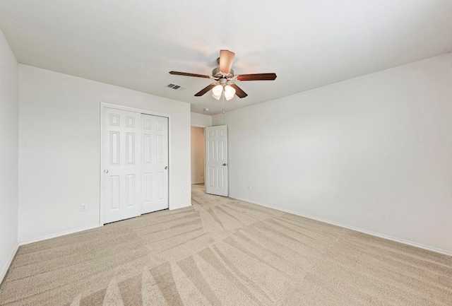 unfurnished bedroom with light carpet, a closet, baseboards, and a ceiling fan