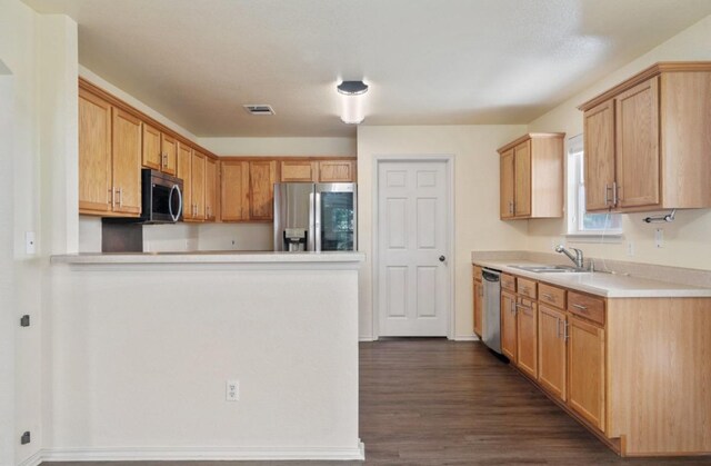 13306 James Monroe St, Manor, TX 78653 - kitchen with appliances with stainless steel finishes, a sink, dark wood finished floors, light countertops, and a peninsula