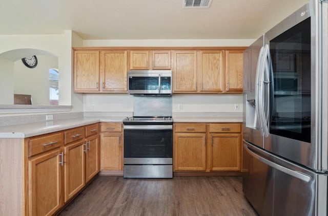 13306 James Monroe St, Manor, TX 78653 - kitchen with appliances with stainless steel finishes, dark wood-style flooring, light countertops, and arched walkways
