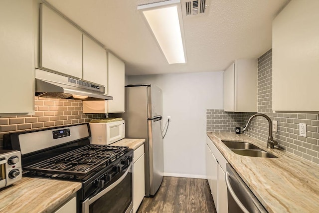 1800 Lavaca St Unit A-514, Austin, TX 78701 - kitchen featuring stainless steel appliances, under cabinet range hood, a sink, dark wood-type flooring, and tasteful backsplash