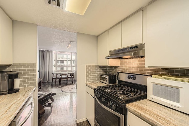 1800 Lavaca St Unit A-514, Austin, TX 78701 - kitchen featuring stainless steel gas range, under cabinet range hood, wood finished floors, rail lighting, and tasteful backsplash