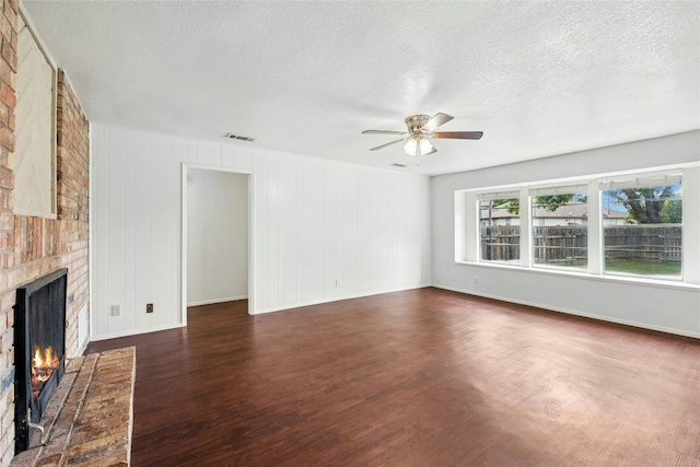 unfurnished living room featuring a ceiling fan, a fireplace, wood finished floors, a textured ceiling, and baseboards