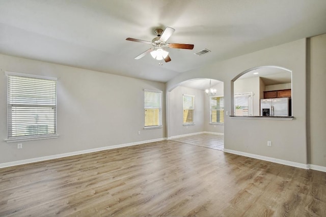 352 Voyager Cv, Kyle, TX 78640 - spare room with arched walkways, a ceiling fan, a chandelier, light wood-style flooring, and baseboards