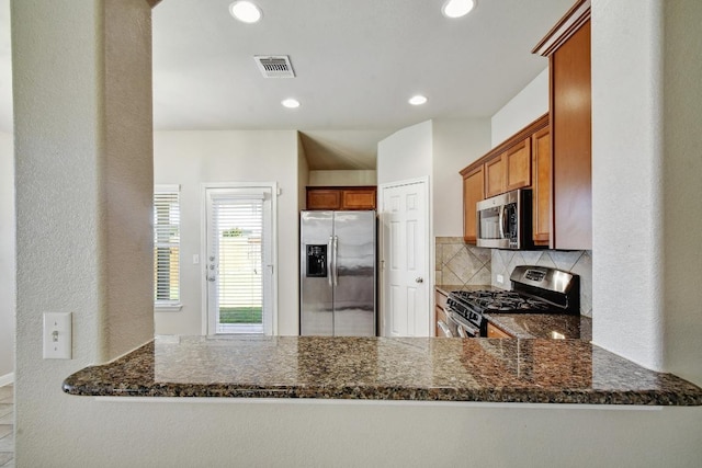 352 Voyager Cv, Kyle, TX 78640 - kitchen featuring stainless steel appliances, a peninsula, decorative backsplash, dark stone counters, and recessed lighting