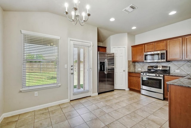 352 Voyager Cv, Kyle, TX 78640 - kitchen with stainless steel appliances, vaulted ceiling, decorative backsplash, brown cabinetry, and a chandelier