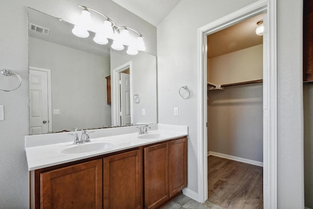 352 Voyager Cv, Kyle, TX 78640 - bathroom with double vanity, a walk in closet, wood finished floors, and baseboards