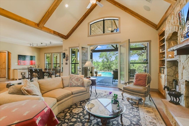 1150 Windmill Run, Wimberley, TX 78676 - living room with a stone fireplace, high vaulted ceiling, beamed ceiling, plenty of natural light, and arched walkways