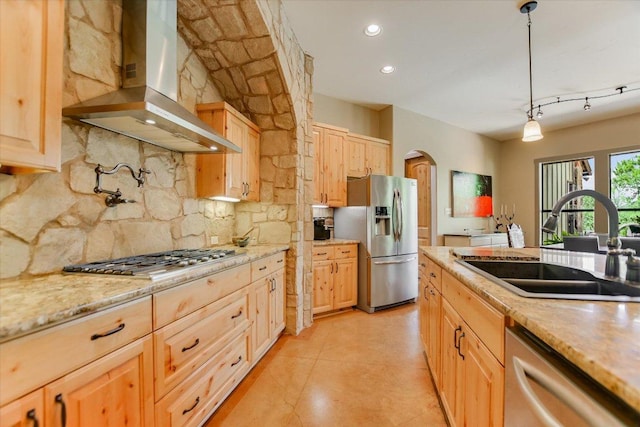1150 Windmill Run, Wimberley, TX 78676 - kitchen featuring appliances with stainless steel finishes, wall chimney range hood, a sink, arched walkways, and light brown cabinetry