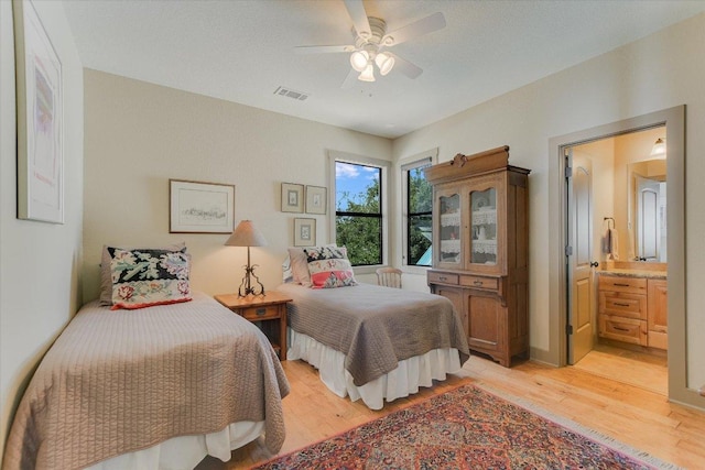1150 Windmill Run, Wimberley, TX 78676 - bedroom with light wood-style flooring, ensuite bathroom, and a ceiling fan